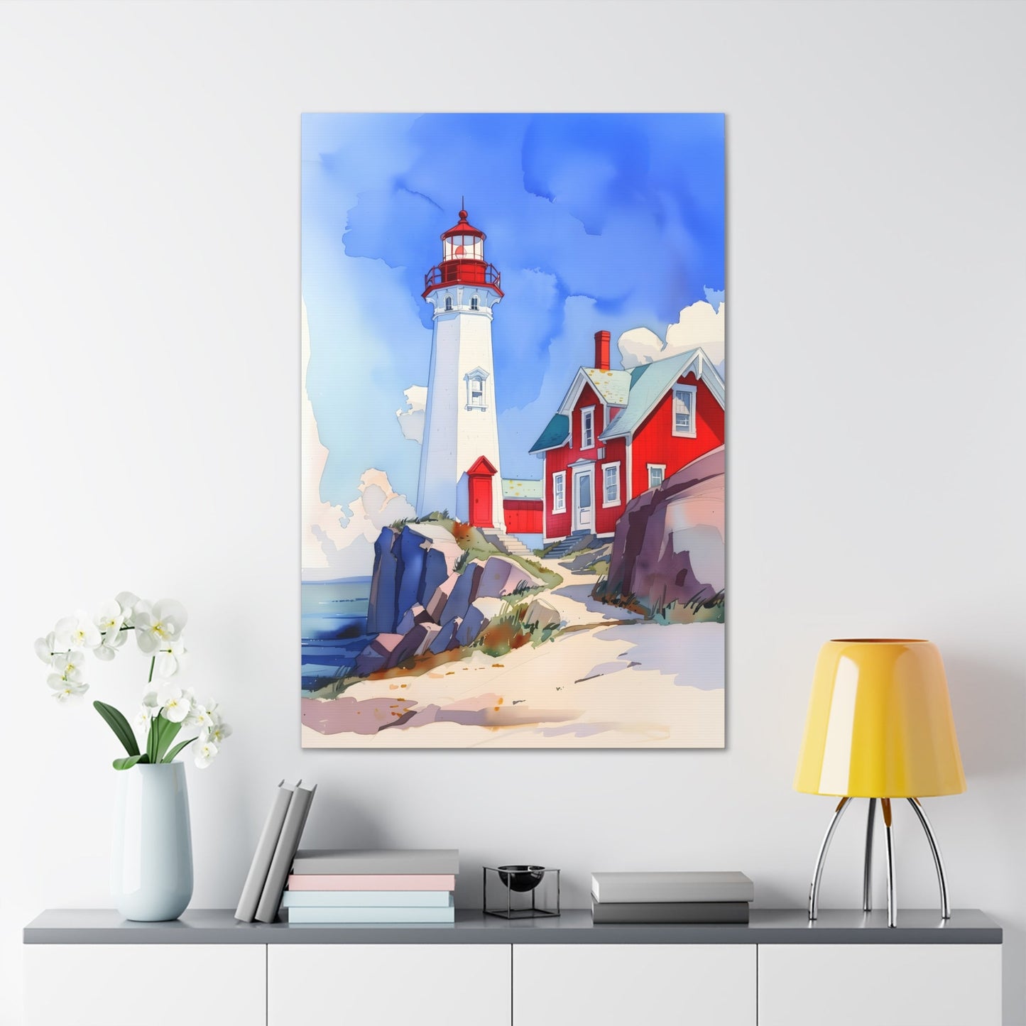 Vertical-oriented wall art: A watercolor-style painting of a lighthouse perched on rocky cliffs overlooking a vast ocean. The sky is painted in shades of blue with wispy white clouds, and the rugged coastline is depicted in intricate detail.