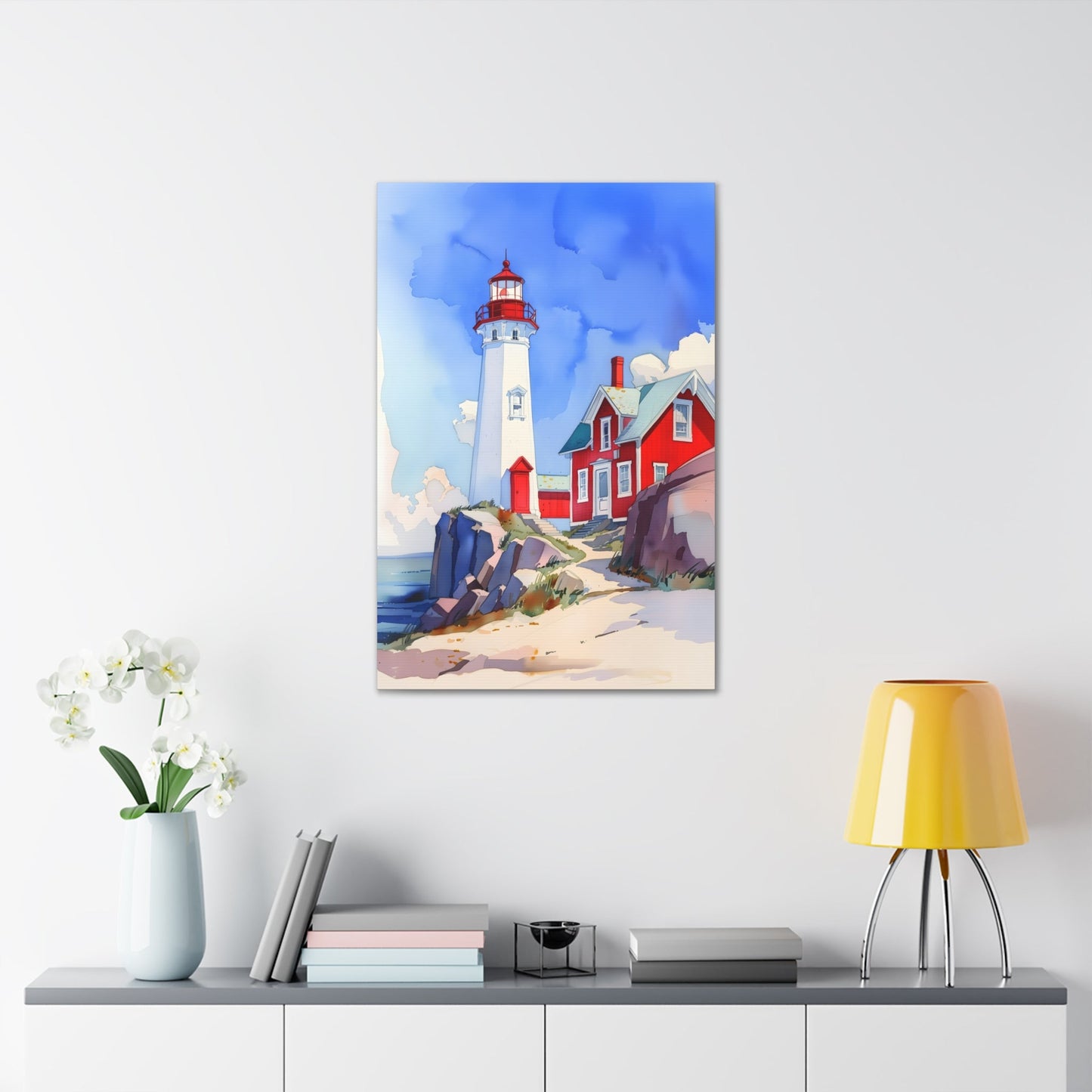 Vertical-oriented wall art: A watercolor-style painting of a lighthouse perched on rocky cliffs overlooking a vast ocean. The sky is painted in shades of blue with wispy white clouds, and the rugged coastline is depicted in intricate detail.